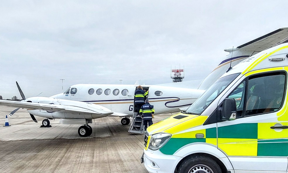An ambulance on the tarmac, at an airport for collection of Airside Transfer Ambulance Biggin-Hill emergency. The airplane is on the left and the ambulance collection is in the foreground on the right.