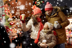 Happy family enjoying the festive atmosphere at Frankfurt's Christmas Market, arriving in style via private aircraft hire, surrounded by twinkling lights and holiday decorations