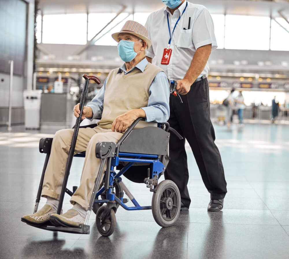 Passenger in wheelchair being assisted through the airport by a medical escort before a commercial flight 