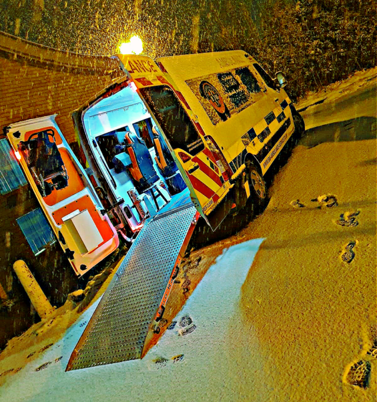 SkyCare ground ambulance on a mountain road in the Swiss Alps, preparing for repatriation of a ski injury patient to the UK. 